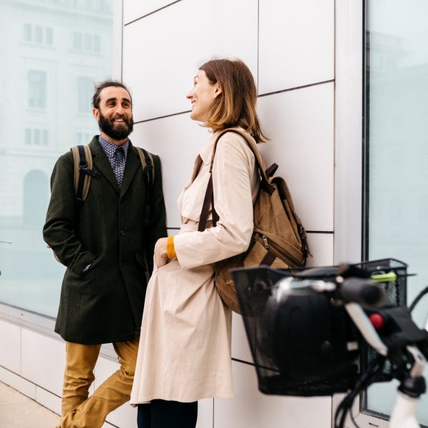 Man and woman with e-bikes standing at a building talking